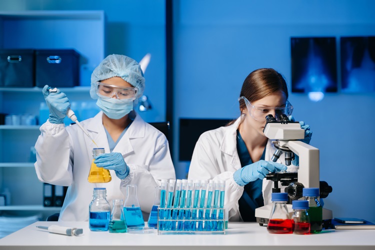 Young scientists conduct research investigations in the lab, a researcher in the foreground uses a microscope in the THCO lab