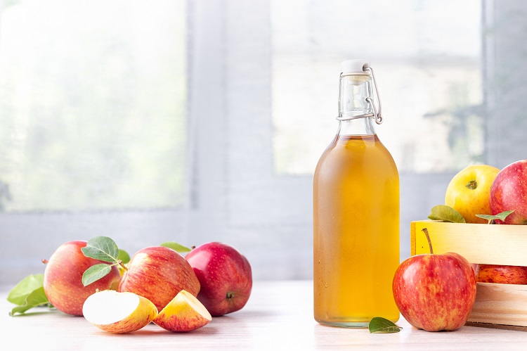 A table with apples and apple vinegar on it