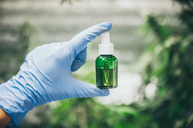 A hand from a laboratory holding a bottle of CBD oil