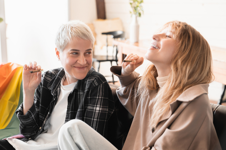 Two adults smoking cigarettes indoors, highlighting indoor smoking habits and related health risks.
