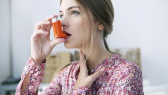 CBD and asthma – woman using an inhaler during an asthma attack