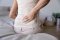 A woman sitting on a bed with sciatic nerve inflammation.