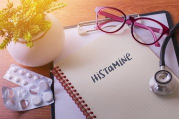 En notesbog med “histamin”, omgivet af medicinske redskaber og tabletter.