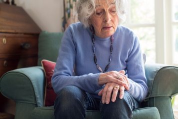 Ældre kvinde, der sidder i en lænestol og lider af Parkinsons sygdom