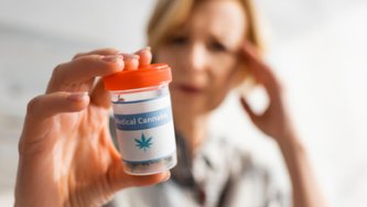 A woman suffering from migraines holds a box of CBD capsules.
