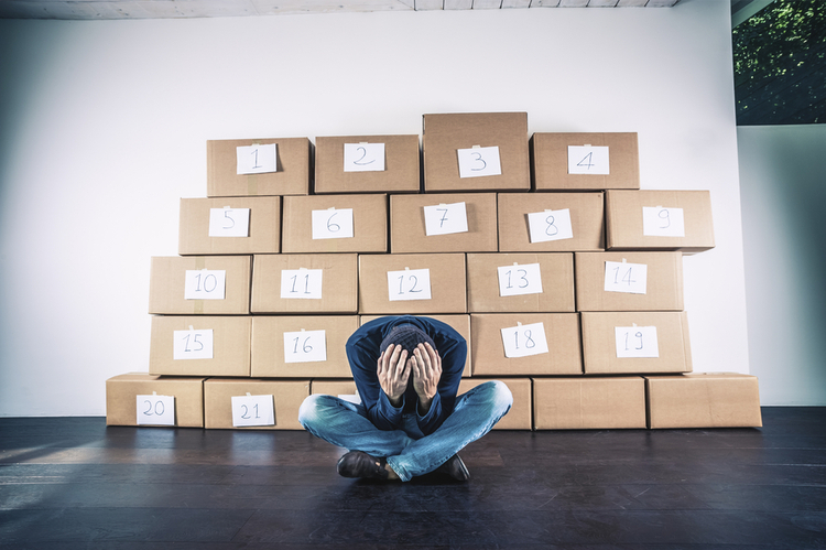 A man sitting on the floor with his face covered in front of a wall of numbered boxes – a visual metaphor for obsessive-compulsive disorder (OCD).