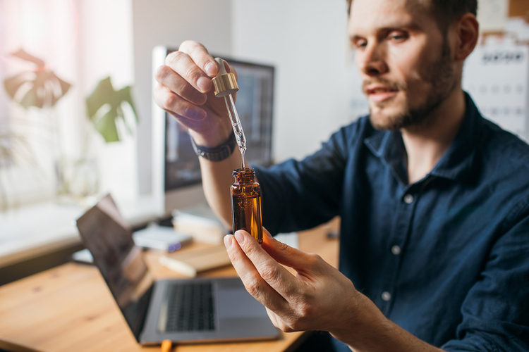 Man using CBD oil dropper – concept of natural sciatic pain relief