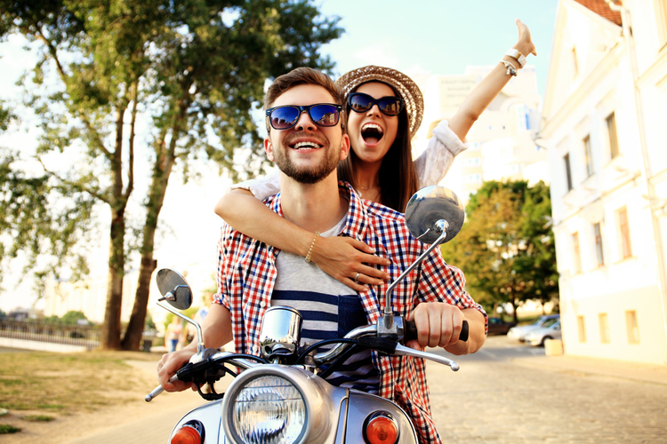 A man and a woman traveling on a scooter