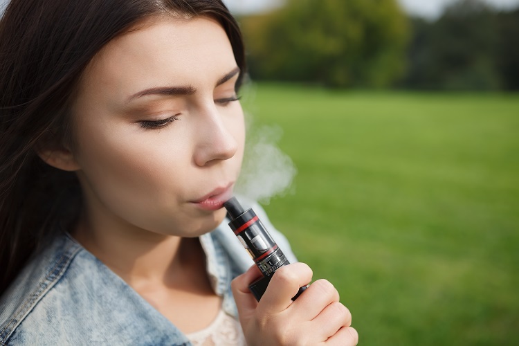 Woman holding a pocket vaporizer and vaping