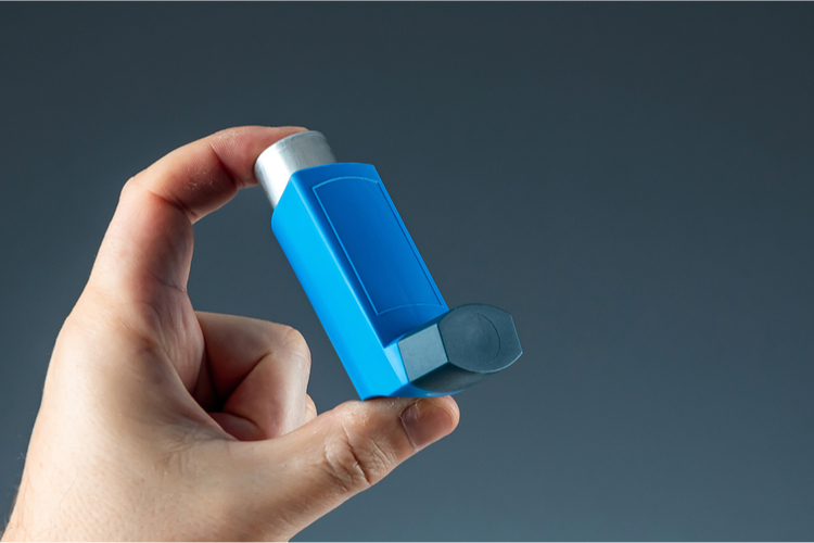 Close-up of a hand holding a blue pocket asthma inhaler