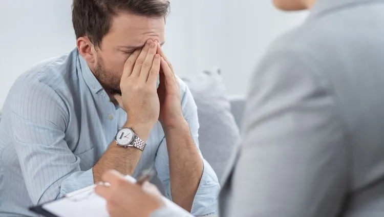 A man with his head bowed during a conversation with a therapist during a psychiatric consultation about treatment options for bipolar disorder