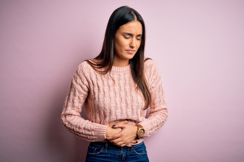 Woman holding her stomach because of the side effect of CBD